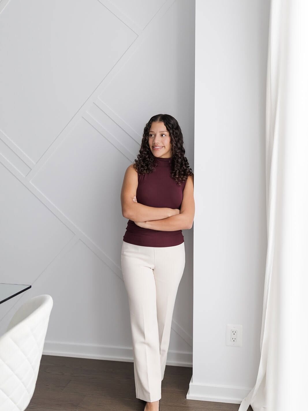 Jaelyn Cruz leaning on a white column, arms crossed